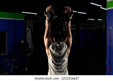 Latino Man With Sportswear, Doing Press With A Pair Of Kettlebells In A Gym