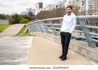 Latino man in sportswear leaning on railing at outdoor training area looking confidently at the camera. - Powered by Shutterstock