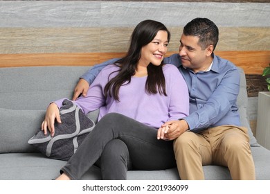 Latino man and woman couple sitting in an sofa in the living room enjoying their company and sharing their love with quality time without having children - Powered by Shutterstock