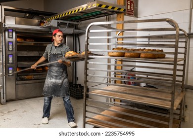 Latino master baker taking the loaves out of the oven and putting them to cool - Powered by Shutterstock