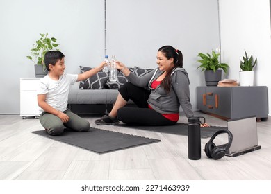 Latino mom and son drink water, hydrate and listen to music after exercising, tired and happy to do their physical activity together, spend quality time together as a family
 - Powered by Shutterstock