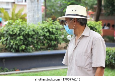 
Latino older adult with protective face masks and hat walking in plaza, new normal covid-19