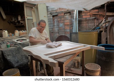 Latino older man working the wood sitting