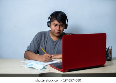 Latino Student With Headphones Typing In Front Of Laptop. Mexican Teenager