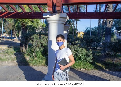 Latino Student Taking Notebook, Wearing Medical Facial Mask. Mexican Teen