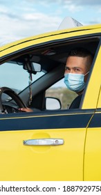 Latino taxi driver sitting inside his yellow car ready to work all day, wearing a mask for protection against the covid19 flu