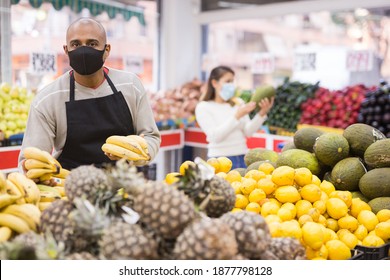 Latino-american Worker In Medical Mask In Supermarket With Pineapples During COVID-19 Pandemic