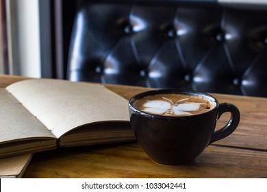 Latte art coffee on wooden table with open blank handmade book background. - Shutterstock ID 1033042441