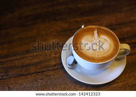 Latte art coffee over wooden background