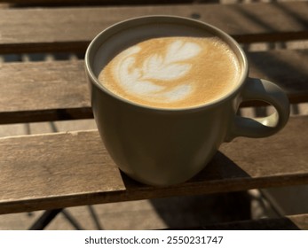 Latte art in a green ceramic cup casting a shadow on a sunlit table - Powered by Shutterstock