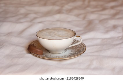 Latte Coffee In Beautiful Porcelain Cup On Bed Sheets