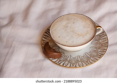 Latte Coffee In Beautiful Porcelain Cup On Bed Sheets