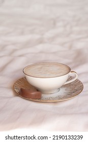 Latte Coffee In Beautiful Porcelain Cup On Bed Sheets