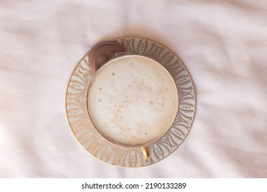 Latte Coffee In Beautiful Porcelain Cup On Bed Sheets