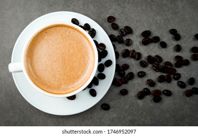 Latte With Frothy Foam, White Coffee Cup And Coffee Beans Top View Close Up On Grey Background.