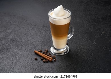 Latte Macchiato In A Tall Glass. Glass Of Coffee Latte And Coffee Beans With Cinnamon Stick On A Dark Slate Background.