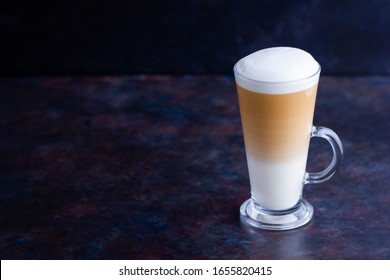 Latte Macchiato In A Tall Glass On A Dark Background. Cafe Latte Layered With Milk In A High Drinking Glass. Сopy Space