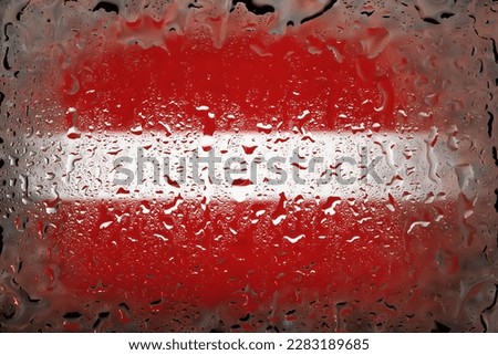 Latvia flag. Latvia flag on the background of water drops. Flag with raindrops. Splashes on glass. Abstract background