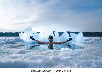 Latvia. Kadaga Lake. January 10, 2021. Young Man Taking An Ice Bath. Swimming In A Frozen Lake During Winter. Healthy Cold Swim.