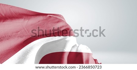 Latvia national flag cloth fabric waving on beautiful grey light Background.