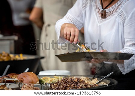 Latvian national cuisine. A woman puts hot dishes from a large pan.