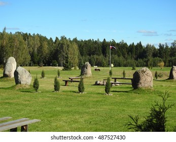 Latvian stonehenge near forest with Latvian flag.