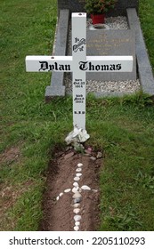 Laugharne Wales September 2022. The Grave Of The Welsh Poet, Writer Dylan Marlais Thomas In The Graveyard Of St Martin's Church. Born 27 October 1914, Died 9 November 1953. Simple White Wooden Cross. 