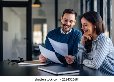 Laughing adult man, holding the company files and giving them to his colleague. - Shutterstock ID 2124326684