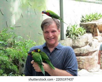 Laughing adult man with a lorikeet on his head