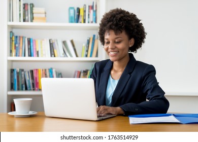 Laughing african american business trainee working at computer indoors at home or at office