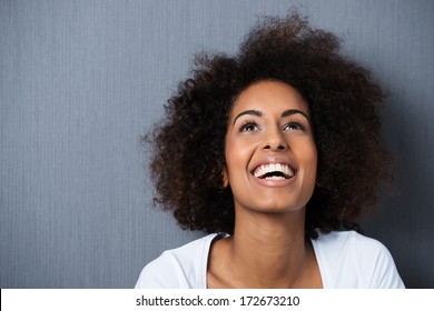 Laughing African American Woman With An Afro Hairstyle And Good Sense Of Humor Smiling As She Tilts Her Head Back To Look Into The Air