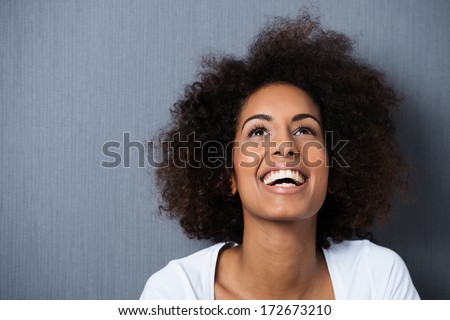 Laughing African American woman with an afro hairstyle and good sense of humor smiling as she tilts her head back to look into the air