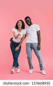 laughing african american woman pointing at camera with boyfriend standing near on pink background  - Shutterstock ID 1176658933