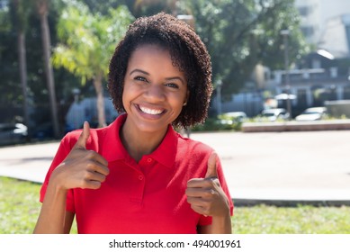 Laughing african american woman showing thumb in the city