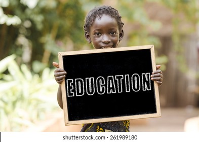 Laughing African Girl with Education on a Chalkboard. Blackboard with written Education on is being hold by an African girl.