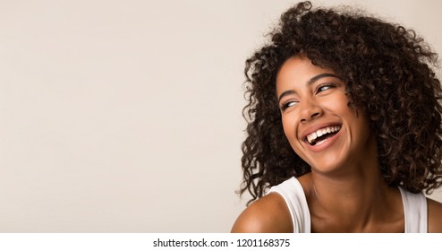 Laughing african-american woman looking away on light background, copy space