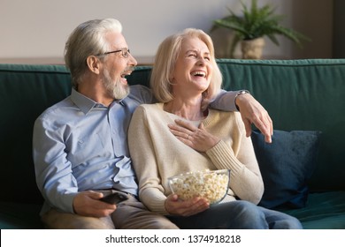 Laughing Aged Couple, Man And Woman Watching Tv, Comedy Show Or Movie And Eating Popcorn Snack, Sitting On Cozy Couch At Home, Mature Family, Man And Woman Enjoying Free Time, Weekend Together