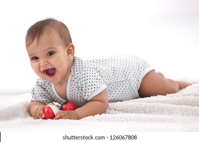 Laughing baby girl with small balls laying on the floor.