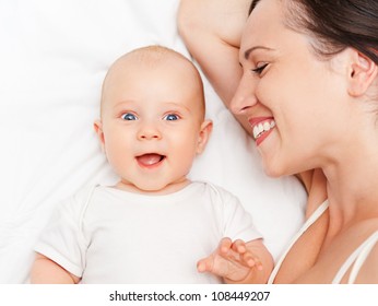 Laughing Baby And Smiley Mother Lying In Bed