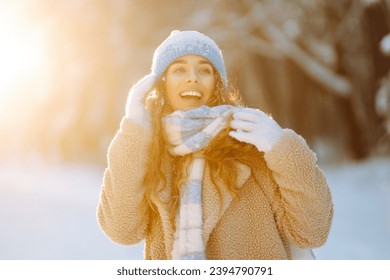 Laughing beautiful woman in the winter forest enjoying an amazing sunset. Great mood on the first snow. The girl is dressed in a fur coat, hat, and scarf. Walking concept. - Powered by Shutterstock