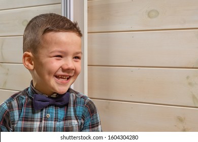 Laughing boy of 4 years old in a blue tart shirt on a light wooden background