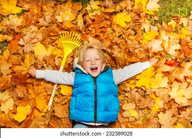 Laughing boy laying on the autumn leaves with rake - Powered by Shutterstock