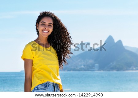 Laughing brazilian woman at Ipanema beach at Rio de Janeiro with beach and mountain in summer