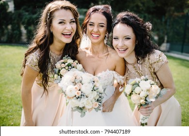 Laughing bride and bridesmaids tell funny stories standing on footsteps outside