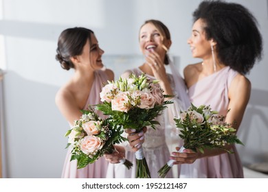 laughing bride and multicultural bridesmaids holding wedding bouquets on blurred background - Powered by Shutterstock