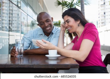 Laughing caucasian woman and african american man looking at mobile phone - Shutterstock ID 685526035
