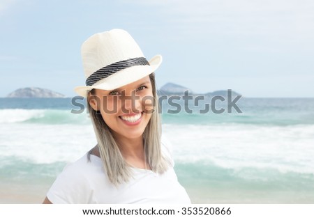 Laughing caucasian woman with hat at beach