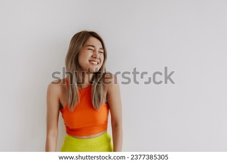 Laughing and cheerful asian woman dress in orange lemon isolated on white.