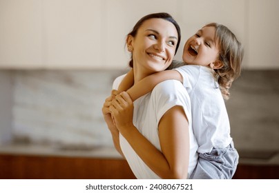 Laughing child embracing her joyful mother while they playing together at home, happy little girl wrapping her arms around mom, sharing moment of pure joy and connection in a light-filled room - Powered by Shutterstock