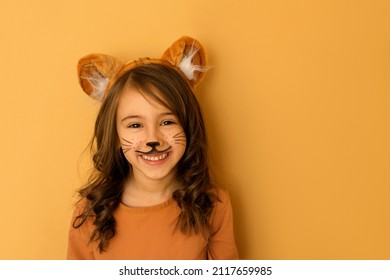 Laughing child with painted moustaches, with ears in the guise of a tiger. A girl dressed up in the symbol of the new year 2022 according to the Chinese zodiac - Shutterstock ID 2117659985